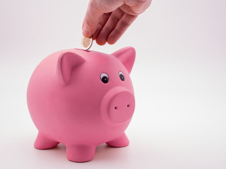Sparschwein mit Hand und Euromünze