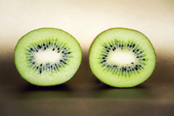 Fototapeta na wymiar Green fresh kiwi split in half on brown background, healthy diet, new year resolution concept
