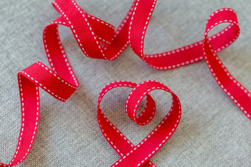 Heart made from red ribbon on linen fabric, Valentine's Day concept.