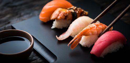 Nahaufnahme von Sashimi-Sushi-Set mit Stäbchen und Soja auf schwarzem Hintergrund