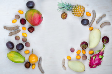 Healthy eating, varieity of fruits on a light background in a frame with copy space, vertical top view. Exotic fruits