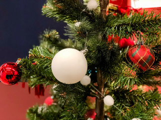 Closeup of red bauble hanging from a decorated Christmas tree. Retro filter effect.