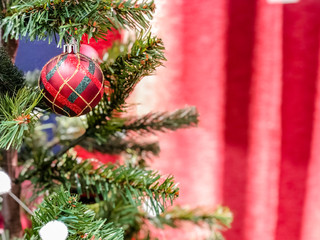Closeup of red bauble hanging from a decorated Christmas tree. Retro filter effect.