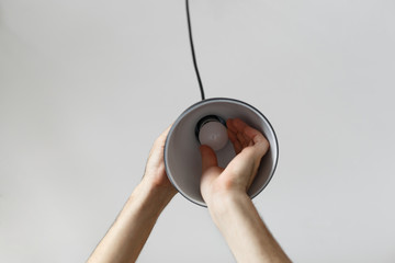 Changing the bulb for led bulb in floor lamp in black colour. On light gray background
