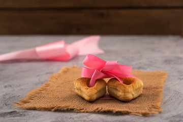 Cookies in the form of a heart with a hole. Two hearts linked by a pink ribbon. The symbol of mutual love. A gift on Valentine's Day.