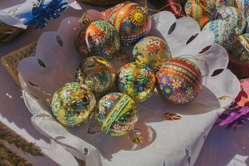 Easter eggs in the basket, traditionally prepared eggs, colorfully painted in decorative patterns and arranged in a basket on a white napkin