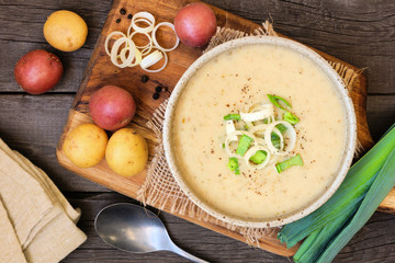 Homemade potato and leek soup. Top view table scene on a rustic wood background.