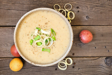 Potato and leek soup. Top view on a rustic wood background.