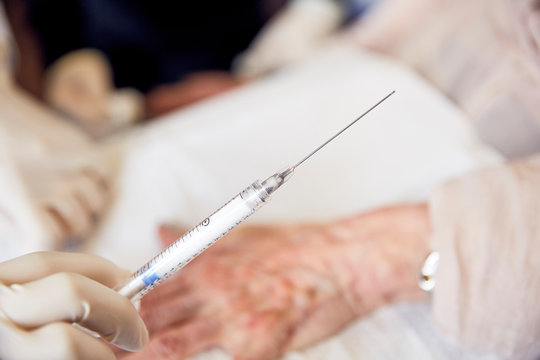nurse holding syringe with patient in background