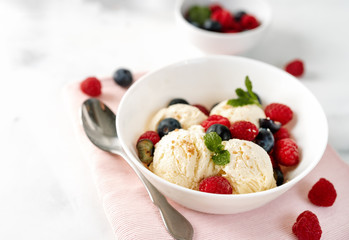 Close up of vanilla ice cream with berries on white table