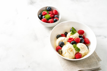 Vanilla ice cream with berries on white table