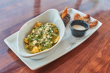 plato de huevos revueltos con salsa, frijol plátanos y crema