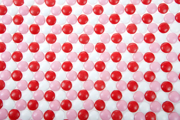 Background of red, pink and white round coated candy treats for Valentine's Day.