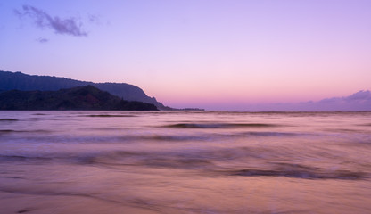 Sunrise lights the dawn sky above Hanalei Bay with the Na Pali coast in the background near Hanalei, Kauai, Hawaii