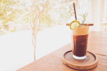Cold ice Americano coffee drink with lemon on wooden table in coffee shop cafe background.Vintage tone.