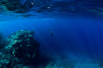 Fototapeta na wymiar Free diver underwater in ocean with rocks and corals
