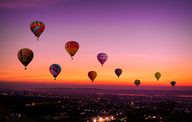 The Colorful hot air Balloons  flying above city on sunset time before dark coming with colorful of light and a beautiful twilight and sunset sky background. - Powered by Adobe