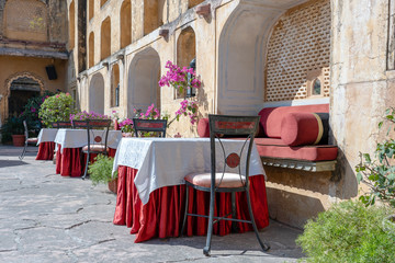 Street cafe in old town, outside in Jaipur, Rajasthan, India. Table, sofa and chairs near old wall