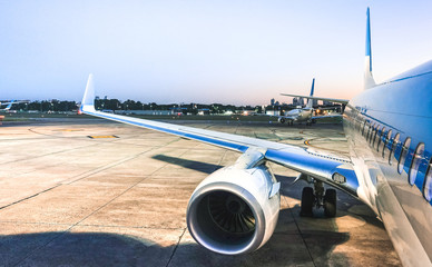 Airplane at terminal gate ready for takeoff at blue hour - Modern international airport with...