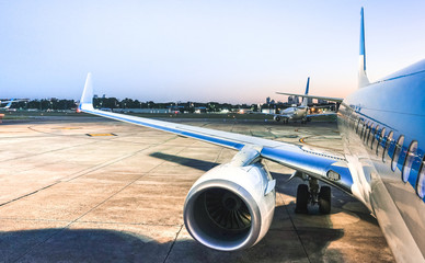 Airplane at terminal gate ready for takeoff at blue hour - Modern international airport with...