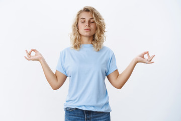 Peace is vital. Portrait of calm and relaxed unbothered young woman meditating with closed eyes and focused face standing in lotus pose, search nirvana with mudra signs, practicing yoga