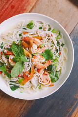 Top view of Spicy rice vermicelli with shrimp, minced pork and chili. Topping with mint leaves.