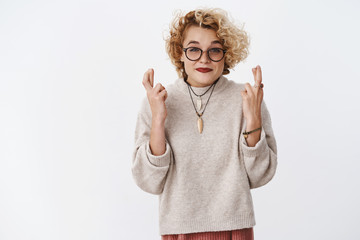 Good-looking excited charming european female in 20s with fair hair in glasses and sweater smiling...