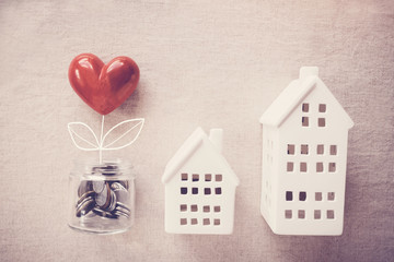 A jar of heart tree growing on money coins and model houses, social responsibility, homeless...