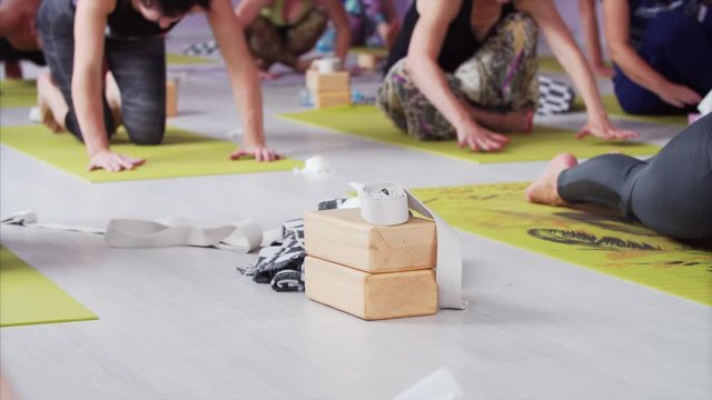 Blanket, wooden bricks and white belts are on the foreground. Blurred people are doing yoga on mats on the background. Ashtanga yoga masterclass
