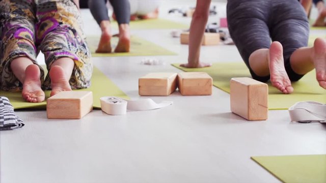 Wooden bricks on the foreground. Unidentified people are doing yoga on mats