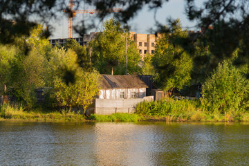 Fototapeta na wymiar wooden house by the river on the background of the city