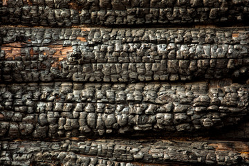 Black charred charred wooden wall. Rough texture. consequences after the fire. fragment of the burned house