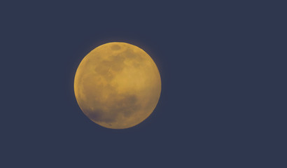 The full moon and its orange brightness is photographed in the night sky from Arizona.