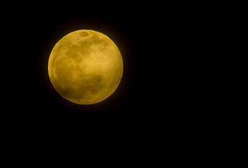 The full moon and its orange brightness is photographed in the night sky from Arizona.