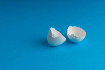 Broken eggshell on the blue background with selective focus