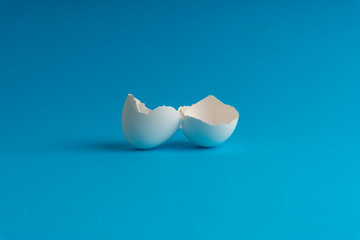 Broken eggshell on the blue background with selective focus