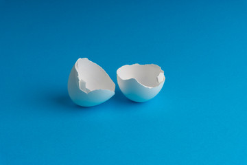 Broken eggshell on the blue background with selective focus