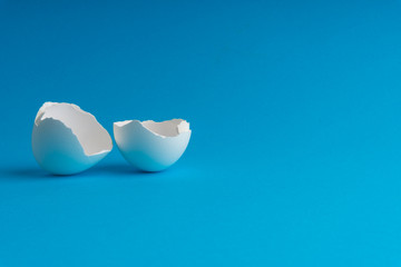 Broken eggshell on the blue background with selective focus