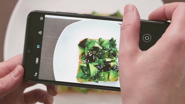 Female Hands Photographing Food For Breakfast, Avocado Toast By Smartphone.