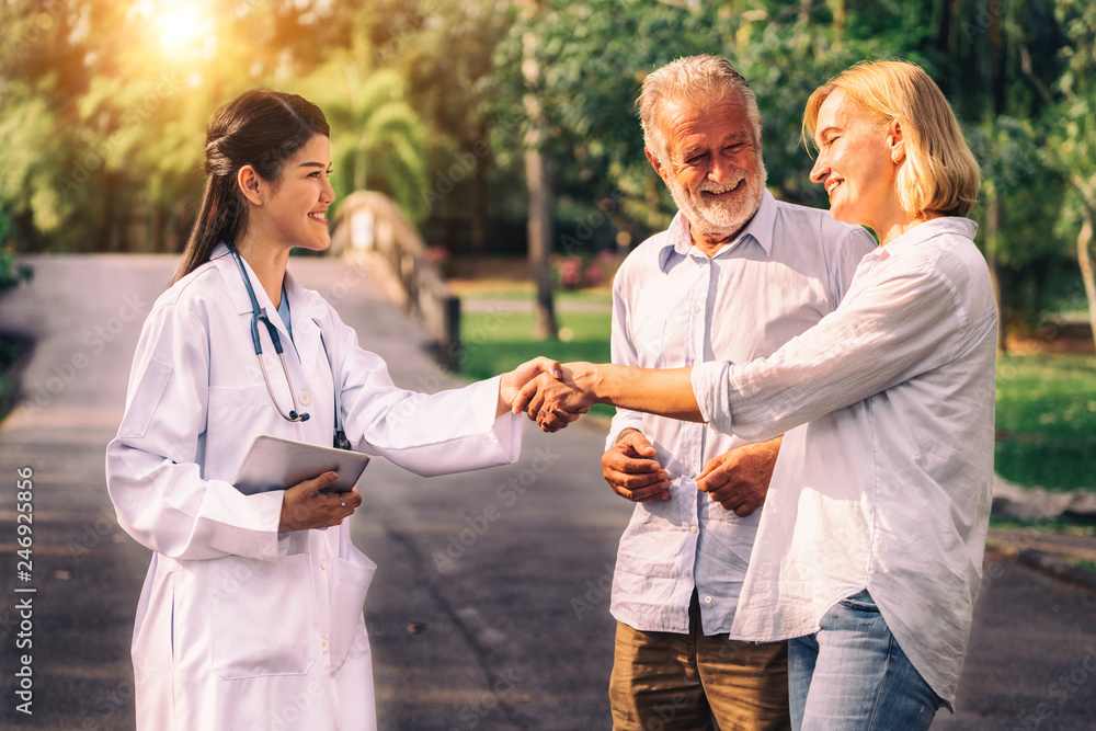 Sticker senior couple man and woman talking to young nurse or caregiver in the park. mature people healthcar