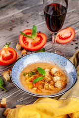 Concept of Spanish cuisine. Tomato soup Gazpacho from fresh tomatoes. Beautiful serving dishes in a blue plate on a wooden table in a restaurant. background image. copy space