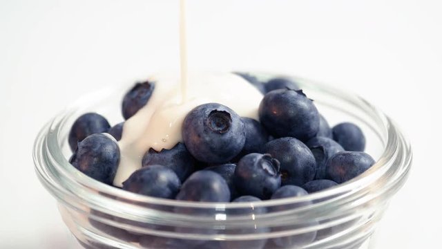 Probiotic Kefir Yogurt Pour on Blueberry Bowl Spinning White Background