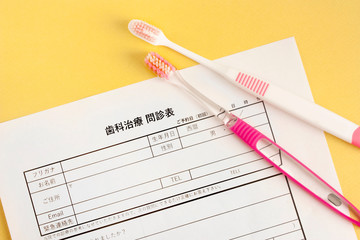 歯の治療の問診票と歯ブラシ、歯医者の予約