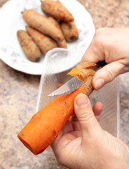 Woman cuts carrots with a knife in the kitchen