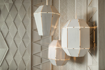Three wooden luminous lamps in modern style. Various forms of lamps hanging from the ceiling.
