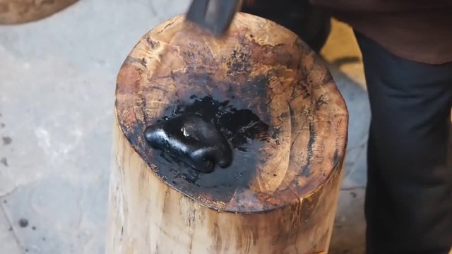 How to make Huizhou inkstick series, step 4, Handicraftsman hitting hot raw ink stick with a massive Hammer on wooden anvil to mix them completely, traditional technology of Chinese culture.