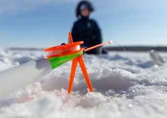 Boy fishing with a fishing rod on the ice in winter