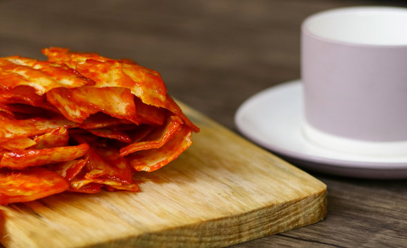 Balado Spicy Chips (cassava Crackers) On Wood Background And A Cup Of Drink.