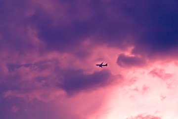 An airplane flying through the clouds at sunset 