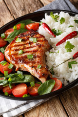 Grilled pork steak with rice garnish and fresh vegetable salad close-up. vertical